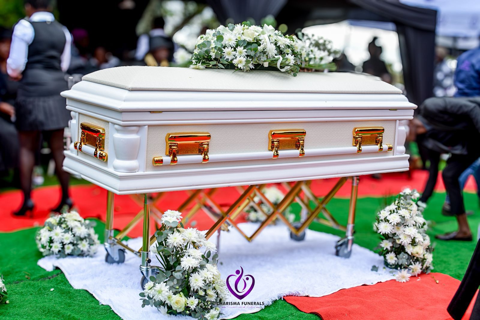 White casket with floral arrangement at graveside