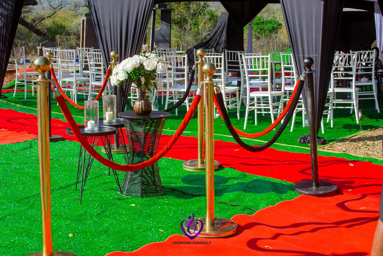 Red carpet graveside setup with chairs